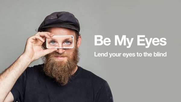 man holding cell phone to his eyes displaying a pair of women's eyes, picture has the words, lend your eyes to the blind
