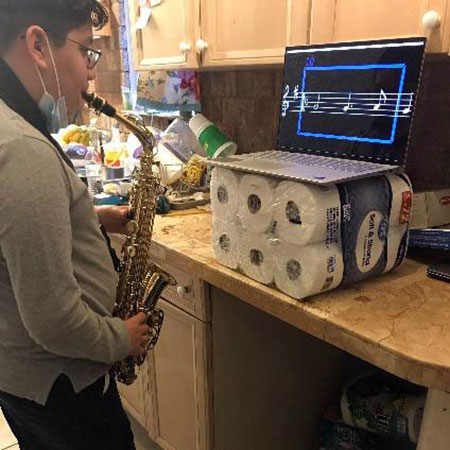 Person practicing saxophone using laptop on toilet paper