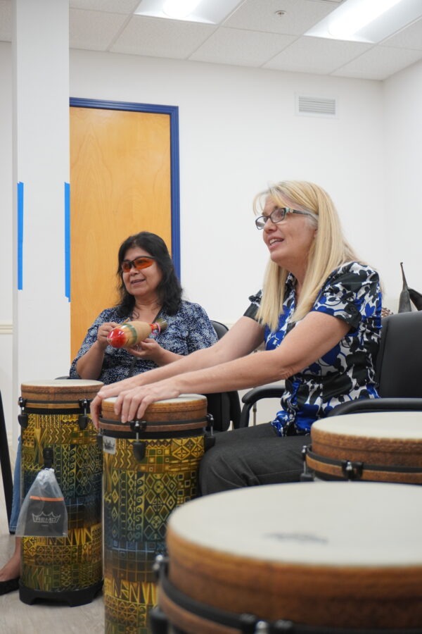 Two women playing hand drums and maracas