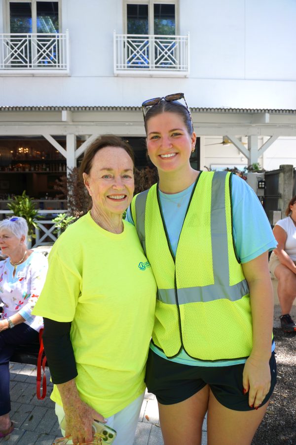 Two smiling volunteers wearing yellow safety vests